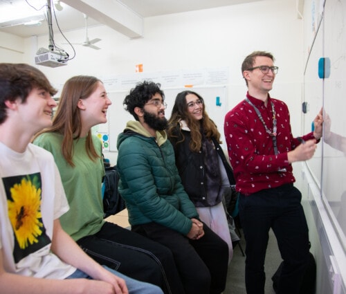 Bob teaching Maths at the white board smilng