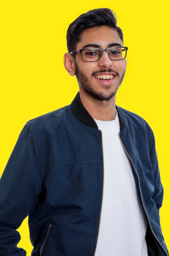 Boy With Glasses Standing Against Yellow Background