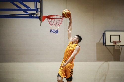 boy shooting ball in basketball hoop