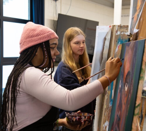 Girl with long hair painting at easel