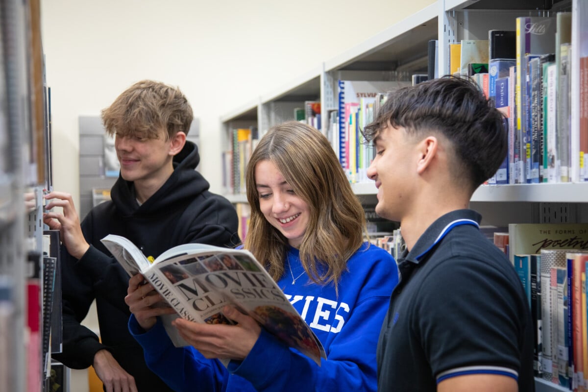 students looking at books in library