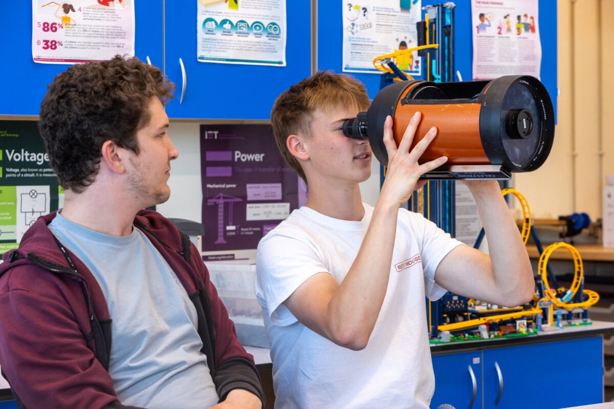 Two physics in a classroom, with one lookign into a cylinder