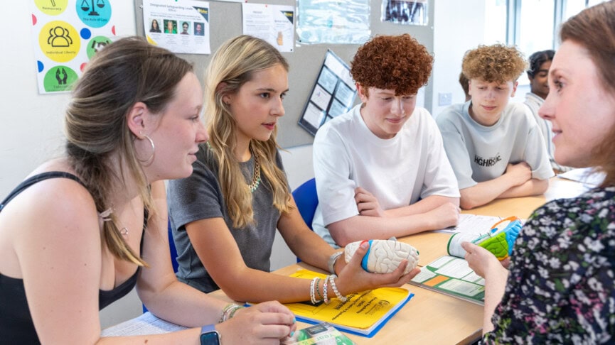 Teacher talking with students holding a plastic brain