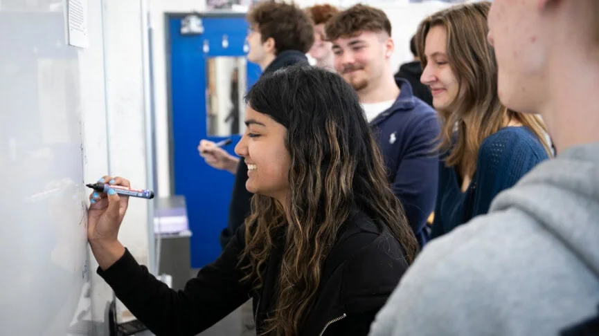 feale math stsudents working out an equation at the whitebaord