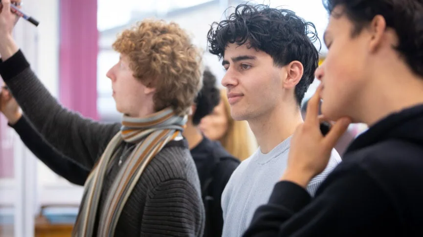 working out a maths problem at the whiteboard