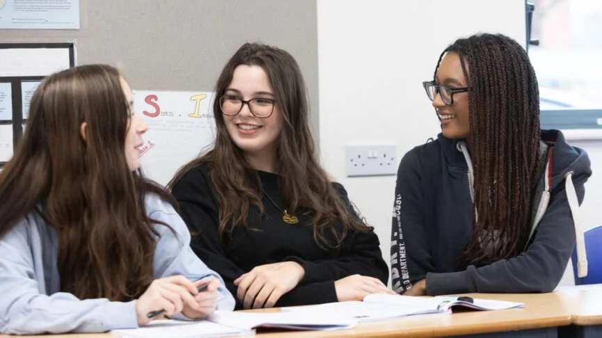 three female students chatting in a psychology classroom