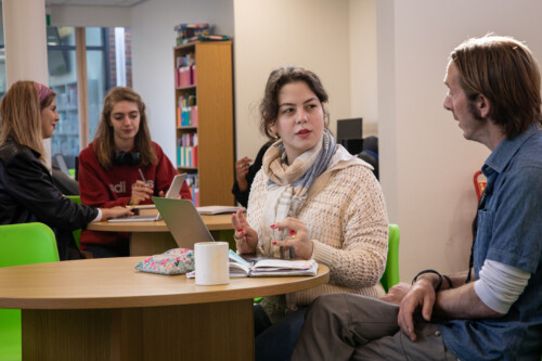 Member of staff sitting with a student in the study centre