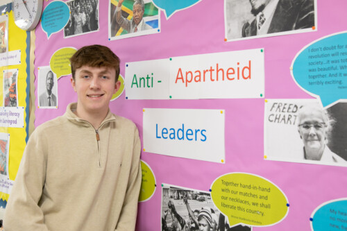 History Oppression and Equality student standing by anti apartheid poster