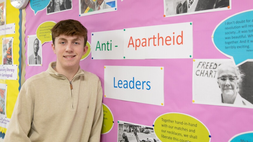 History Oppression and Equality student standing by anti apartheid poster