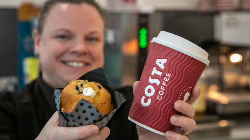 Cafe staff holding out a costa and a muffin