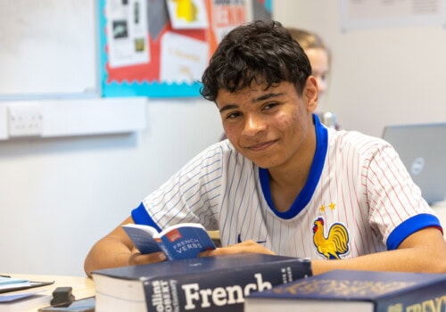 A male student sitting at a desk with a French textbook
