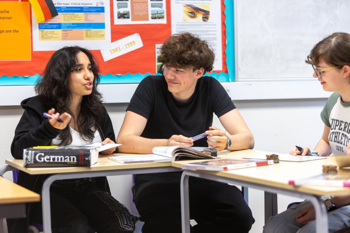 A group of german language students working and talking at their desks