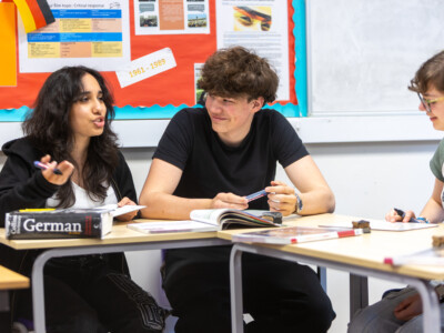 A group of german language students working and talking at their desks