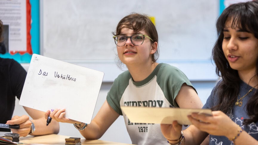 A female student holding up a whiteboard with German writing on it