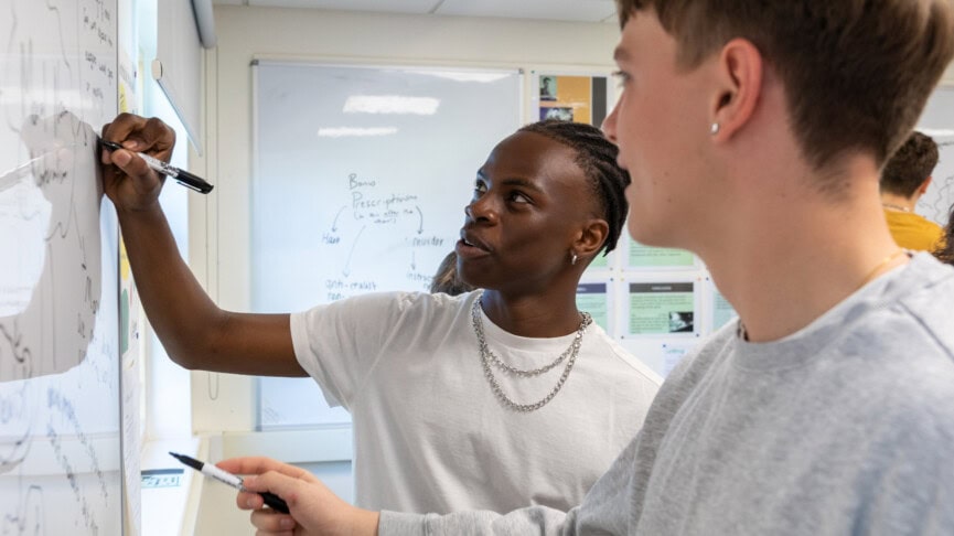 two male students at a whiteboard in a philosophy classroom