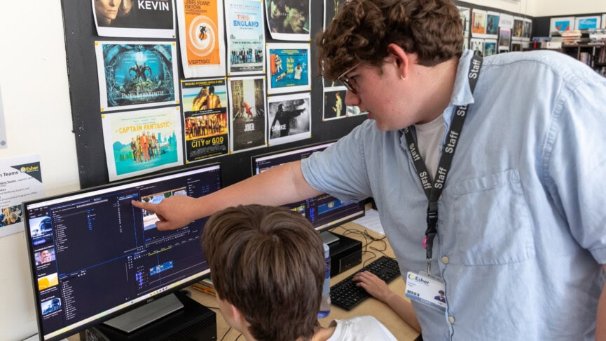 A male film technician helping a student with editing software