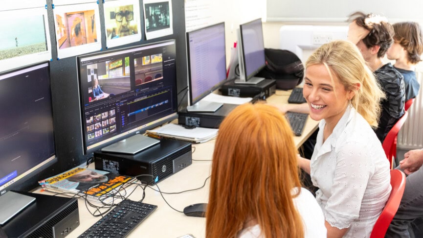 two female students laughing in front of computers