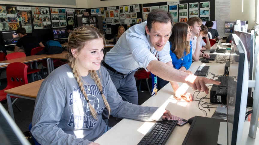 Lee Bone helping a student with work at a computer