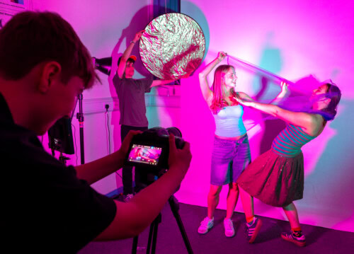 Students on set filming other students with pink lighting