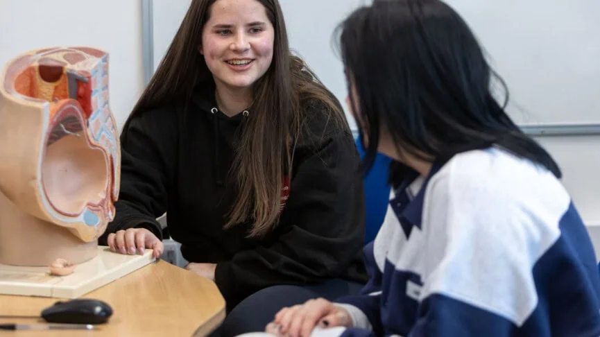 students in front of an anatomy model in a health and social care classroom