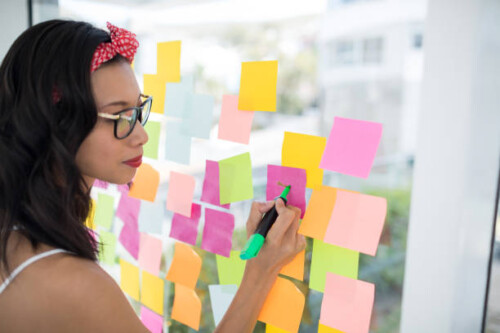 Female Writing On Sticky Notes In Office