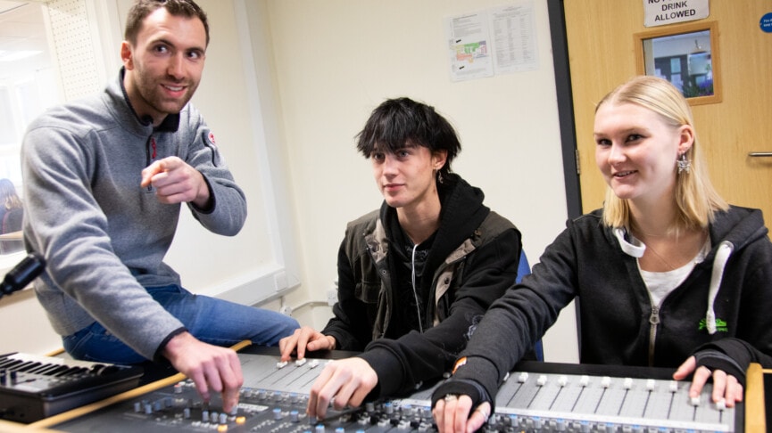 Music teacher with students in recording studio