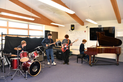 Boys in rock band and a boy playing a piano
