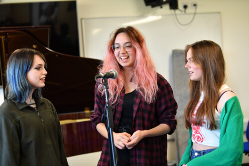 3 female students singing at a microphone