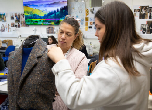 Female student designing a coat at a mannequin