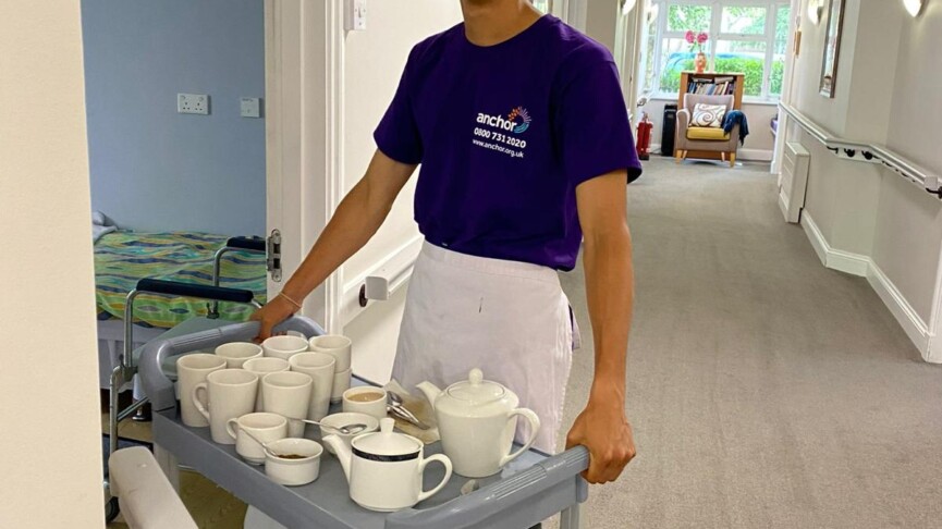 male student delivering tea tray to residents in a care home