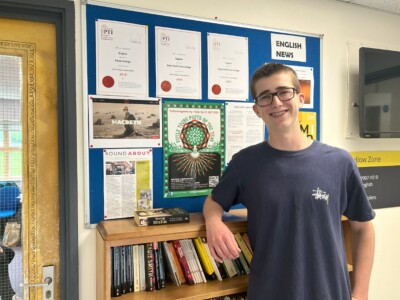Louis standing by the bookcase in the humanities corridor