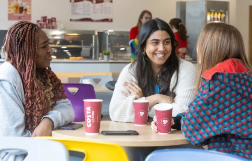 Female students chatting at a table in the cafe with costa