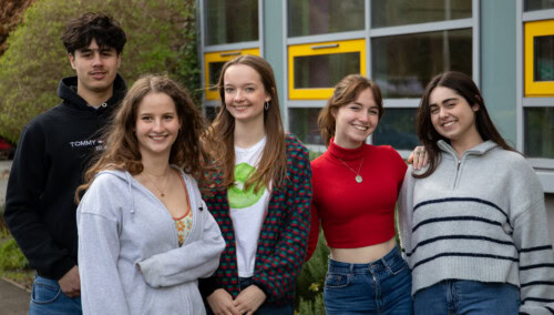 A group of four female and one male student stand ourside the front of Esher Sixth Form College