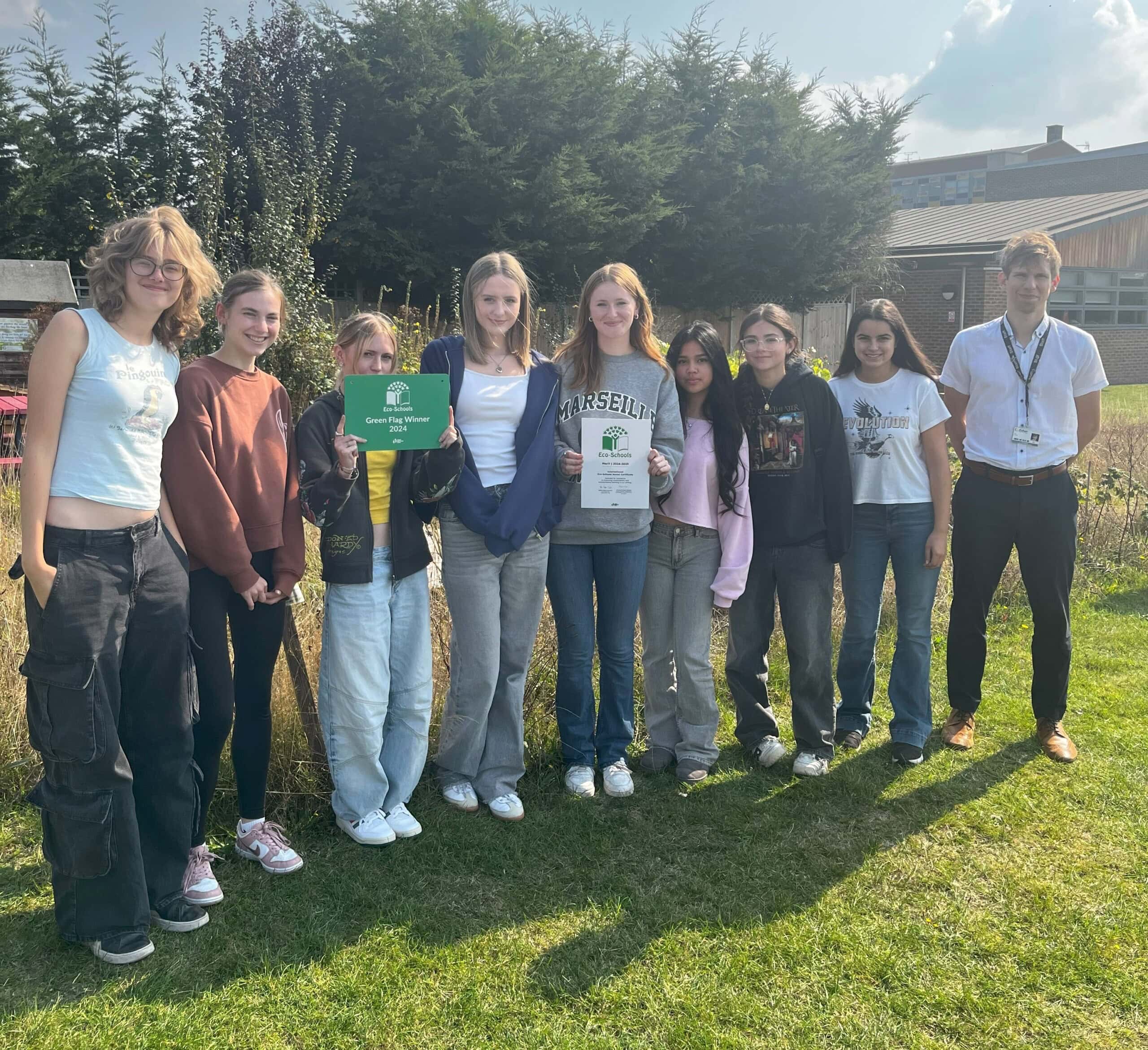 a group of students standing outside with the Green flag award
