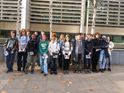 A large group of students standing in front of a corporate building in London