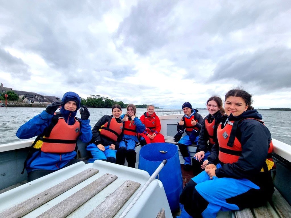 A group of students wearing lifejackets in a boat and smiling
