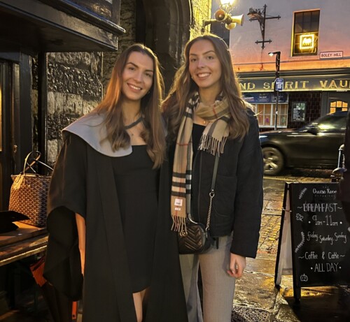 two sisters standing together on a street early evening