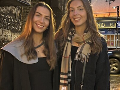 two sisters standing together on a street early evening