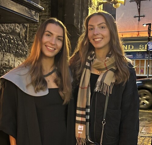 two sisters standing together on a street early evening