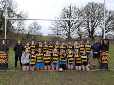 Women's Rugby team posing for a photo underneath the bars