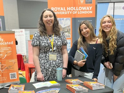 two girls holding prospectuses stand with a university ambassdaor from royal holloway university