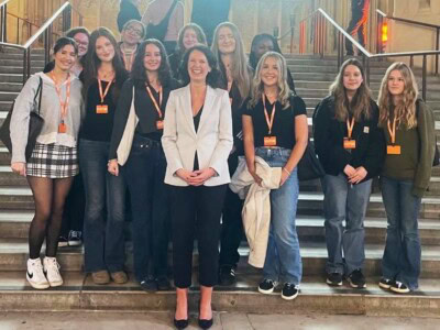 Female Politics students standing on the steps of Parliament with Monica Harding