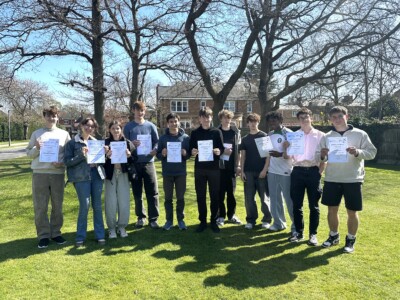 Group of students standing at the front of college holding certificates