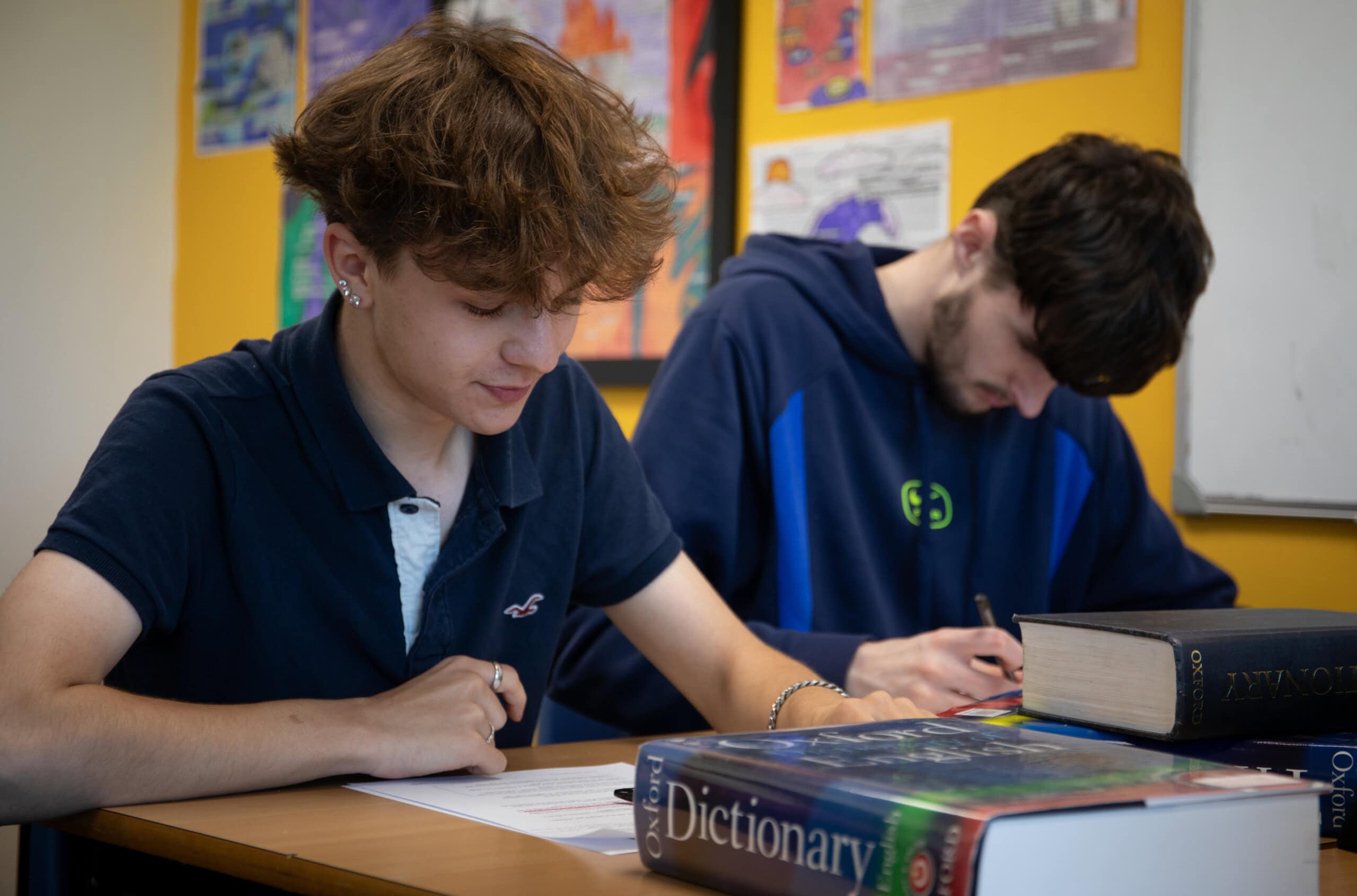 Two male students in an english class writing