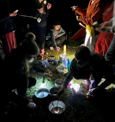 Students cooking marshmallows on a campsite
