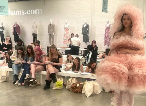 Fashion students drawing a model wearing a fluffy pink dress