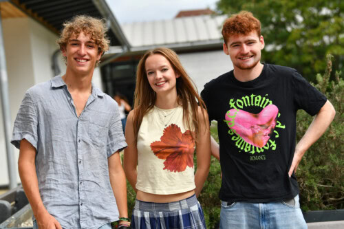 a girl and two boys pose outside on esher college results day