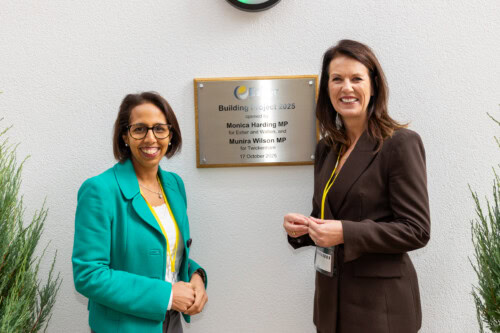 Munira And Monica beside new building plaque