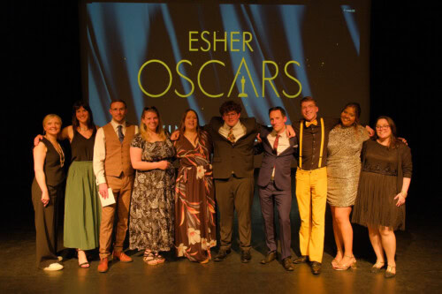 Film teachers stand arms over shoulders in front of an Esher oscars backdrop at the Esher Oscars 2025