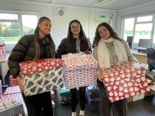 Three students holding the Christmas hampers